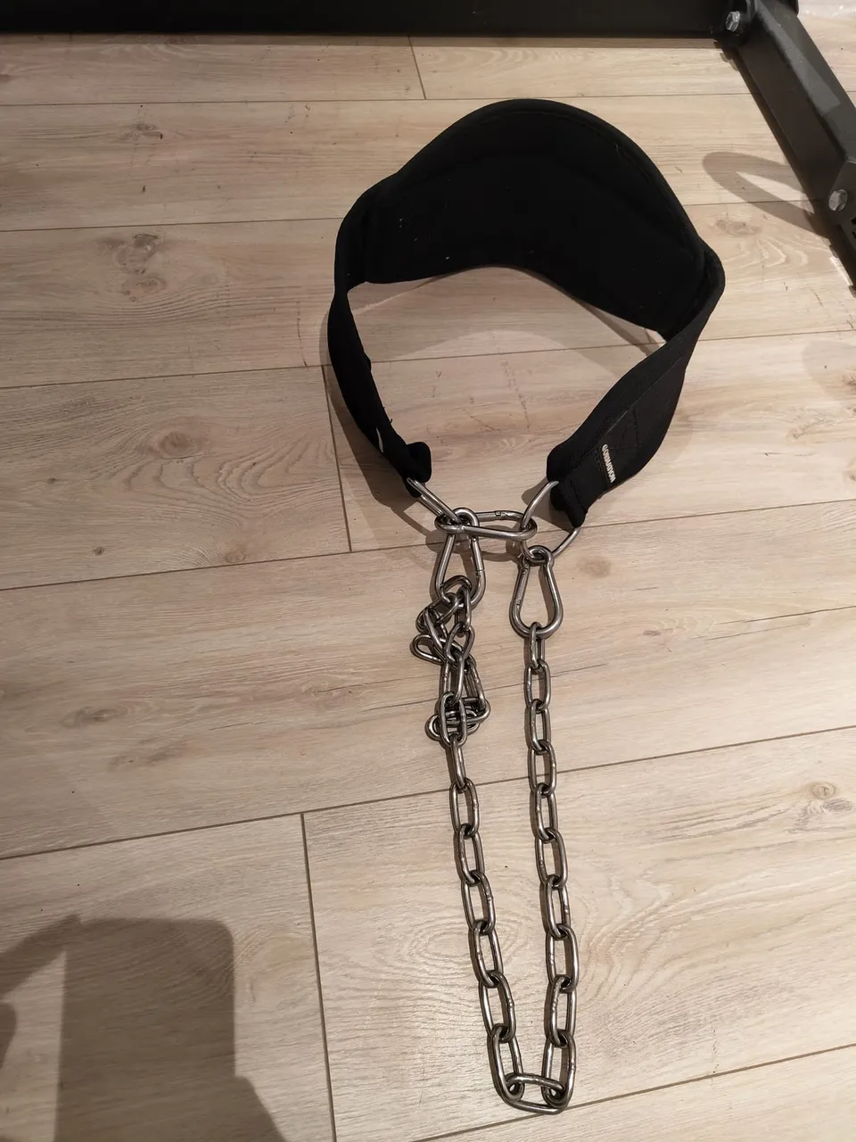 Gornation Premium Dip Belt laid flat on a wooden floor, stainless chain and carabiners stretched out