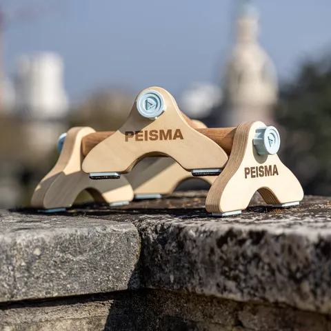 Peisma dismountable wooden parallettes with light blue locking screws, set on a stone wall
